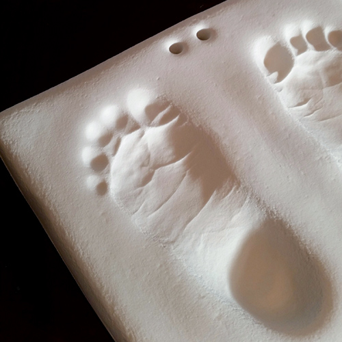 Footprint impressions in white clay to hang